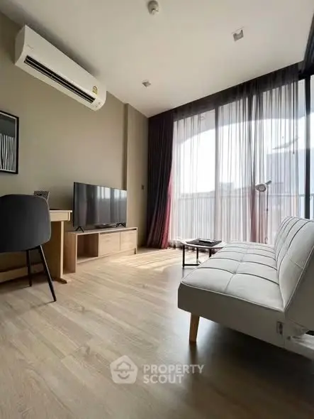 Modern living room with large windows, stylish furniture, and natural light.