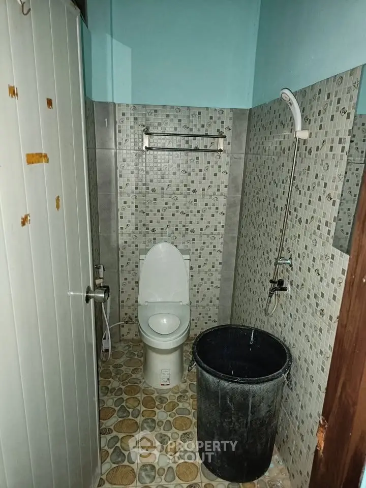 Compact bathroom with tiled walls and floor, featuring a toilet and shower area.