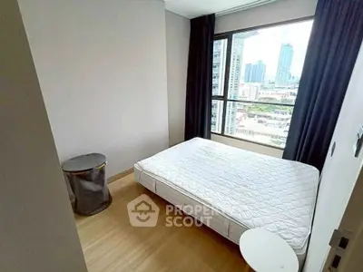 Modern bedroom with city view, featuring a minimalist design and large window for natural light.