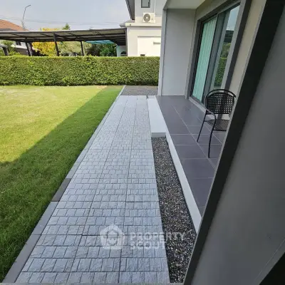 Modern home exterior with patio and lush green lawn, perfect for outdoor relaxation.