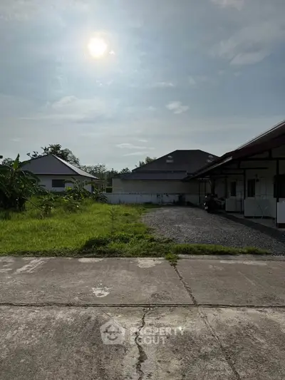 Charming suburban property with spacious yard and modern roof design under a bright sky.