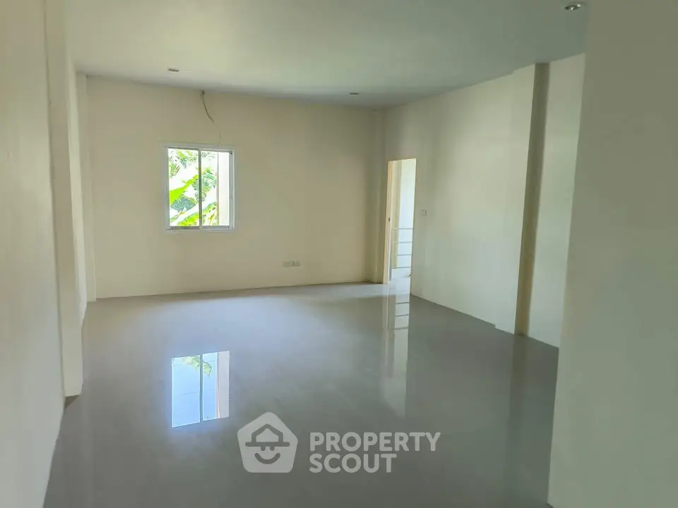 Spacious empty room with glossy floor and natural light from window