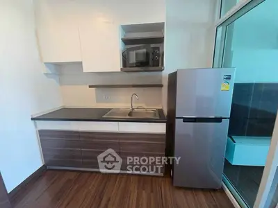 Modern compact kitchen with sleek cabinetry and stainless steel appliances in a stylish apartment.