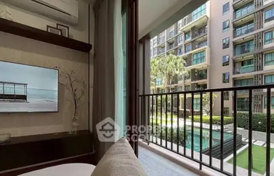 Modern living room with balcony overlooking pool and garden in luxury apartment complex.