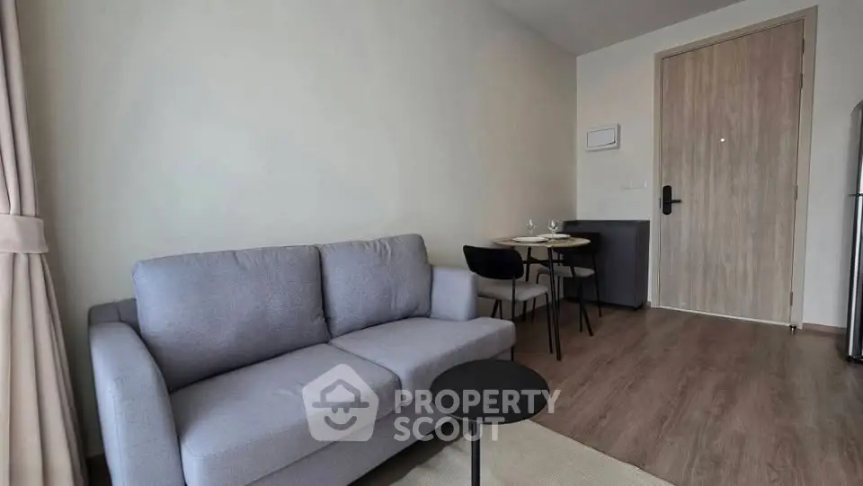 Modern living room with cozy gray sofa and dining area in stylish apartment.