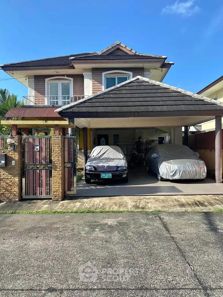 Charming two-story house with covered parking in a serene neighborhood, featuring a well-maintained exterior and gated entrance.