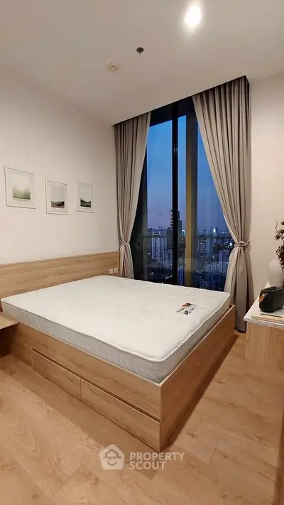 Modern bedroom with large window and city view, featuring wooden flooring and minimalist decor.