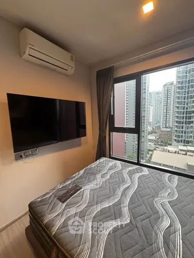 Modern bedroom with city view, featuring a wall-mounted TV and air conditioning.