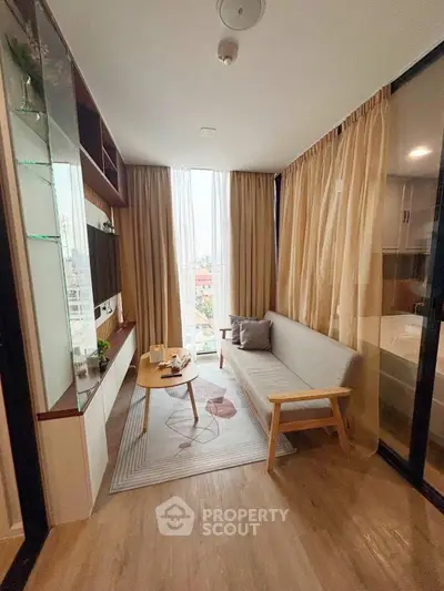 Cozy living room with modern decor and large window offering city views.