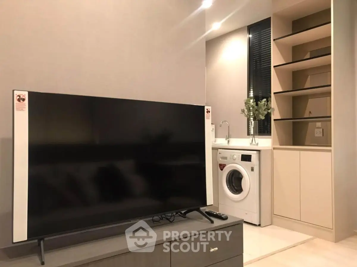 Modern living room with sleek TV and built-in washing machine in stylish apartment.