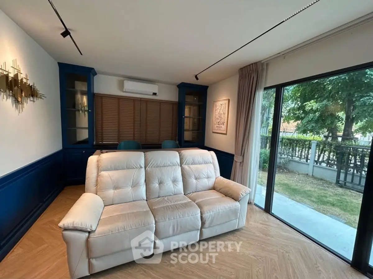 Stylish living room with plush sofa and garden view, featuring elegant blue cabinetry and modern decor.