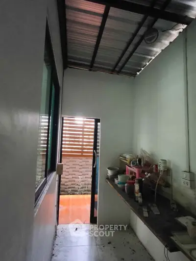 Compact kitchen space with open layout and natural light, featuring basic appliances and outdoor access.