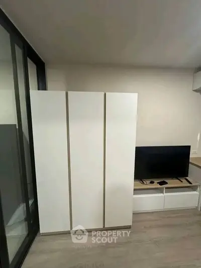 Modern living room with sleek white wardrobe and flat-screen TV