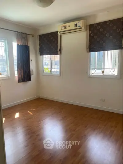 Spacious empty room with wooden flooring and air conditioning, ideal for customization.