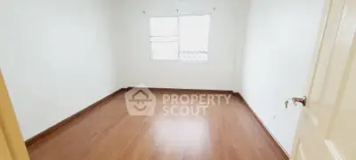 Spacious empty room with wooden flooring and bright window