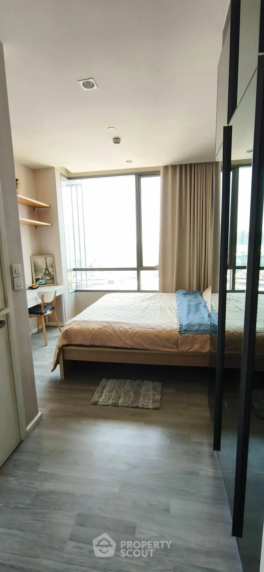 Modern bedroom with large window and stylish decor in a high-rise apartment.