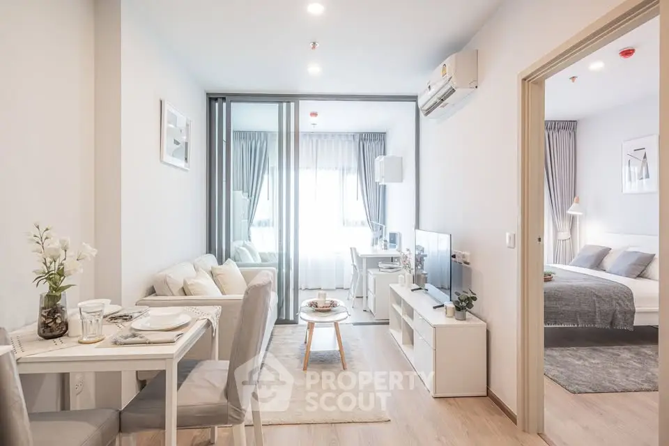 Modern open-plan living room with dining area and bedroom, featuring elegant decor and natural light.