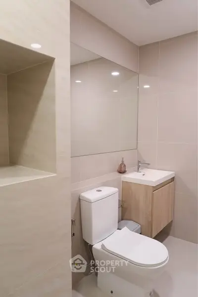 Modern bathroom with sleek fixtures and neutral tones, featuring a compact vanity and toilet.