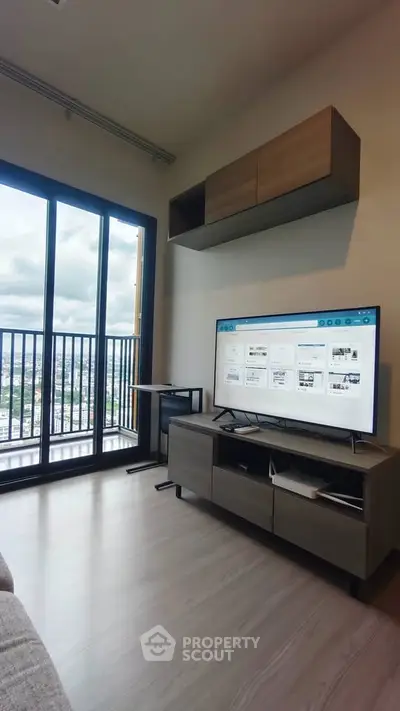 Modern living room with large windows and city view, featuring sleek furniture and a mounted TV.