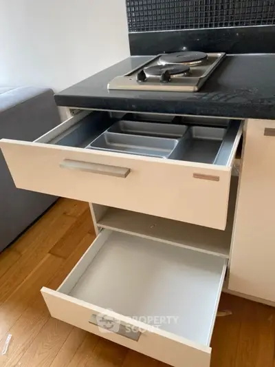 Modern kitchen with sleek drawers and electric stove on black countertop