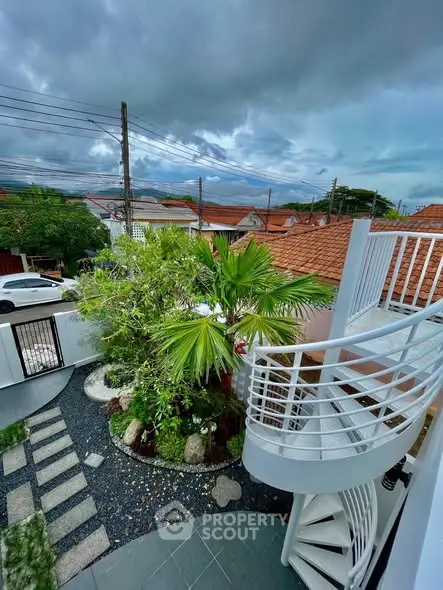 Charming garden view with spiral staircase and lush greenery in a suburban setting.