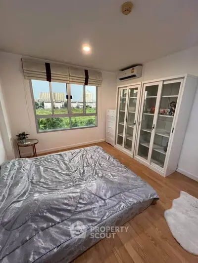Spacious bedroom with large window and modern furnishings, offering a serene view.