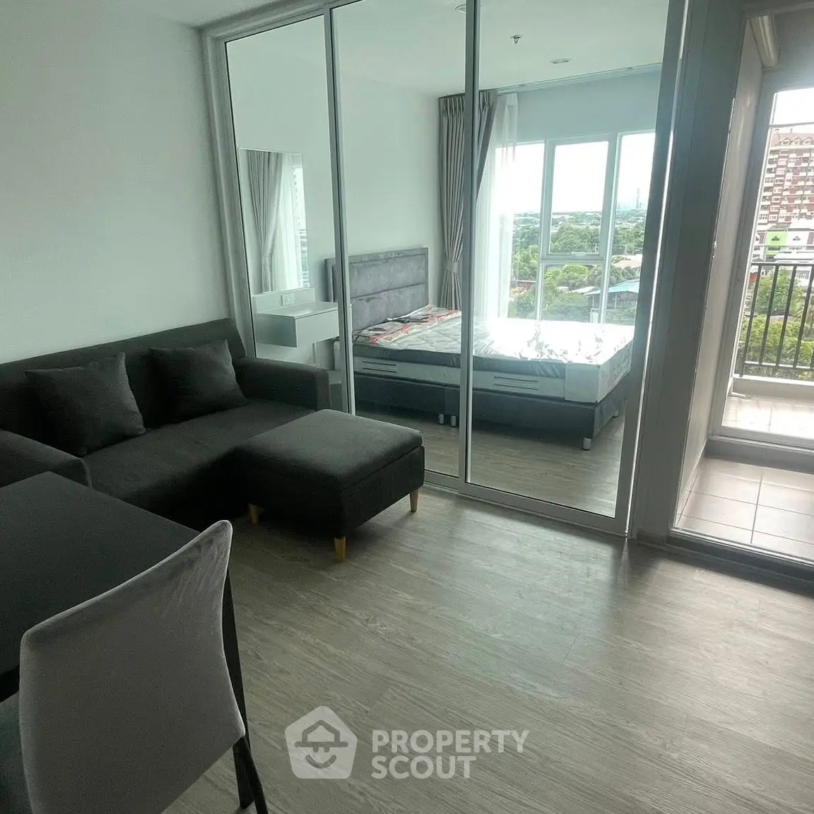 Modern apartment with glass partition, cozy living area, and balcony view.