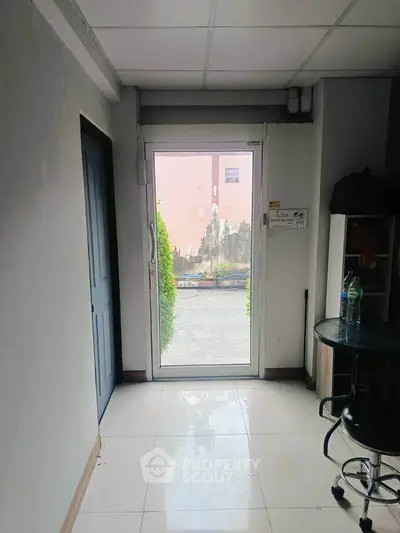 Bright entrance hallway with glass door and tiled floor, ideal for welcoming guests.