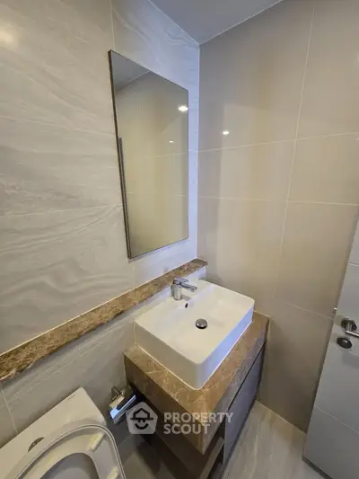 Modern bathroom with sleek sink and mirror, featuring elegant marble accents.