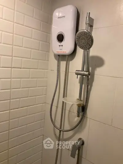 Modern bathroom with electric shower and sleek white tiles.