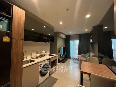 Modern open-plan living room with kitchen, featuring sleek appliances and cozy seating area.