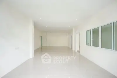 Spacious open-plan interior with glossy tiled flooring and large windows, ideal for modern living.