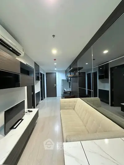 Modern living room with sleek design and neutral tones, featuring a comfortable sofa and wall-mounted TV.