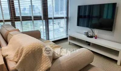 Modern living room with large windows and city view, featuring a cozy sofa and flat-screen TV.