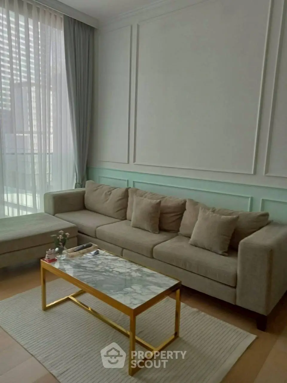 Elegant living room with modern sofa and marble coffee table, featuring floor-to-ceiling windows.