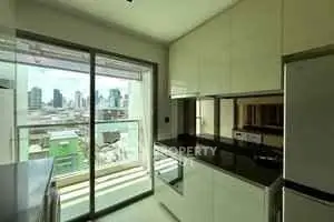 Modern kitchen with sleek cabinetry and city view from large window.