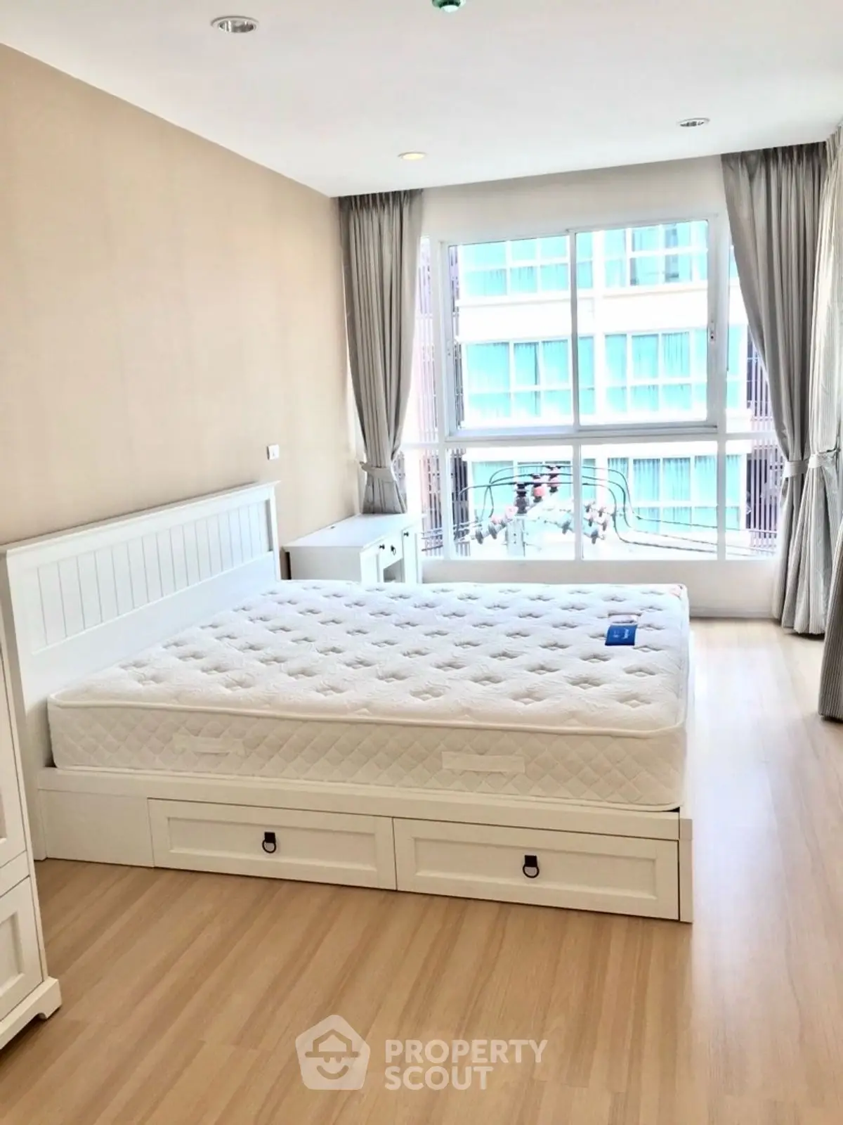 Bright and airy bedroom with large window and modern furnishings in a stylish apartment.