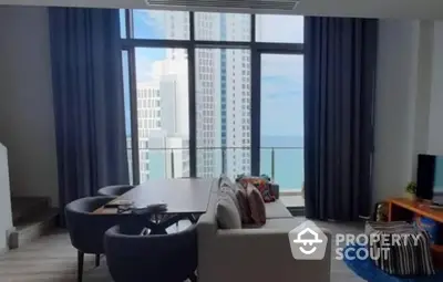 Luxurious high-rise living room with floor-to-ceiling windows offering a panoramic ocean view, complemented by stylish furnishings and ample natural light.