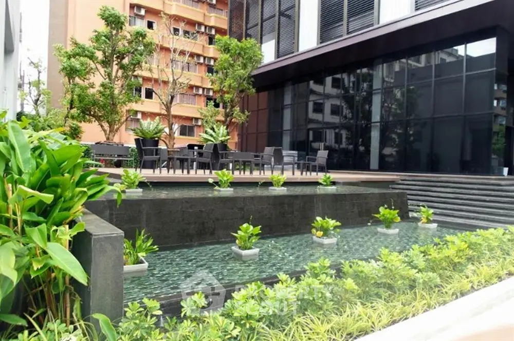 Modern building exterior with lush garden and water feature