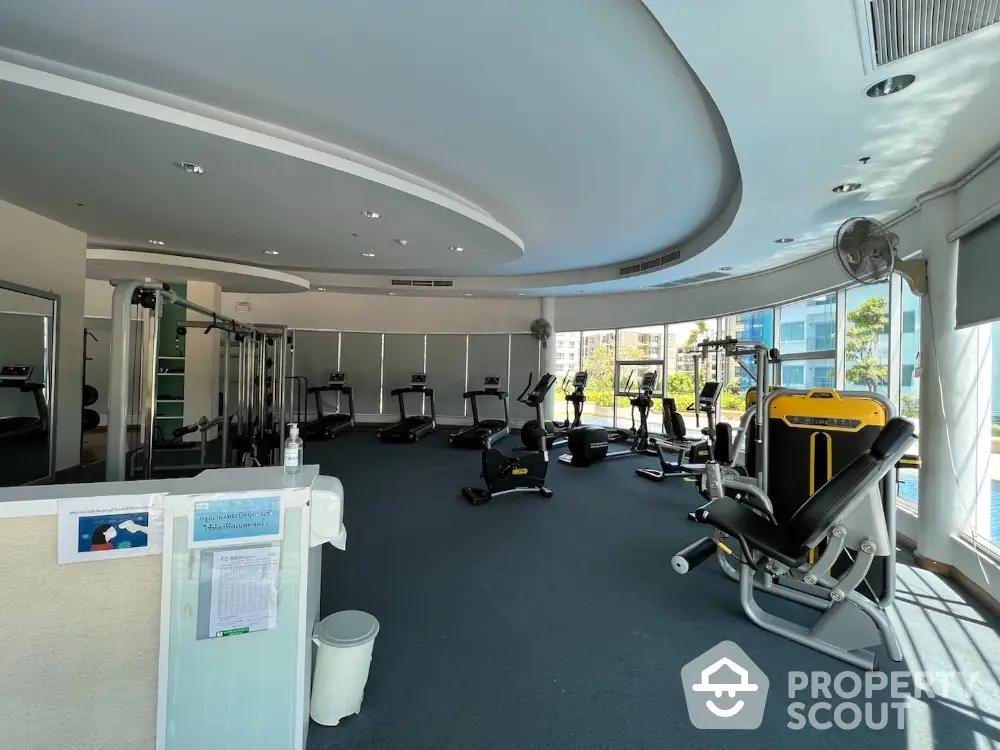 Spacious modern gym with state-of-the-art fitness equipment and large windows offering natural light.