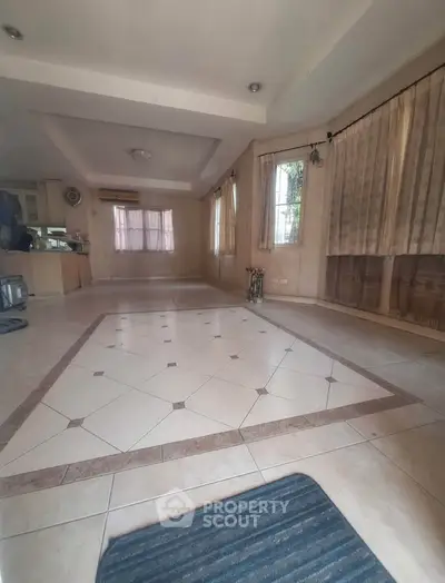 Spacious living room with tiled flooring and large windows, perfect for natural light and open living.