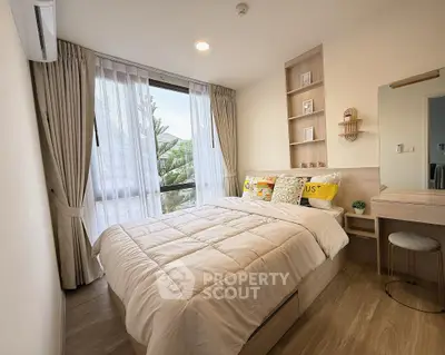 Cozy bedroom with modern decor and large window offering natural light.