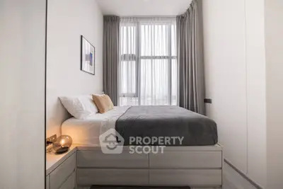 Modern bedroom with large window and stylish decor in a high-rise apartment.