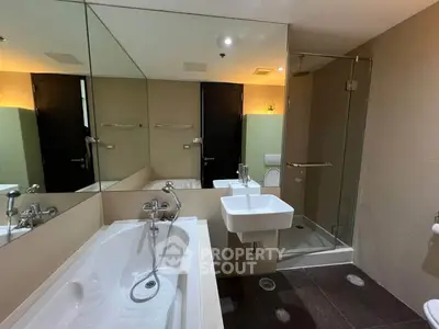 Modern bathroom with bathtub and glass shower enclosure in elegant apartment.
