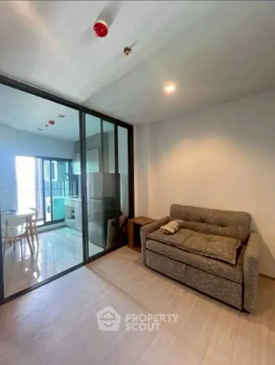 Modern living room with glass partition and cozy sofa in open layout apartment.