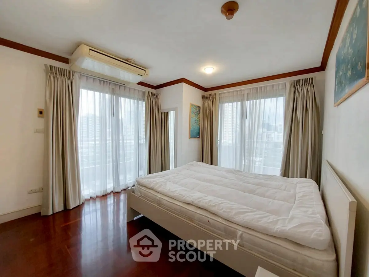 Spacious bedroom with large windows and elegant curtains in a modern apartment.