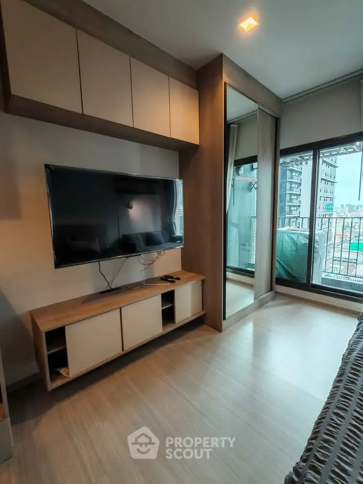 Modern living room with sleek TV setup and large window offering city view