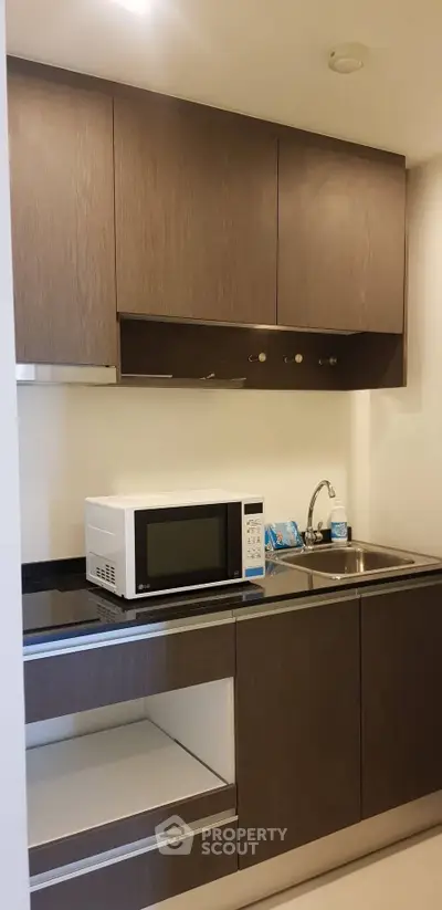 Modern compact kitchen with microwave and sleek cabinetry in urban apartment