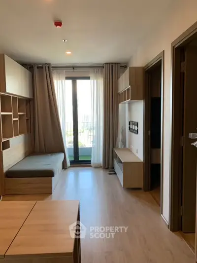 Modern apartment interior with wooden flooring and built-in furniture, featuring a large window with curtains.