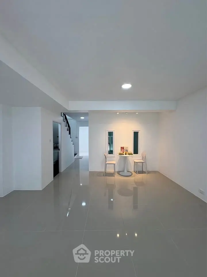 Spacious modern living area with sleek tile flooring and minimalist dining setup.